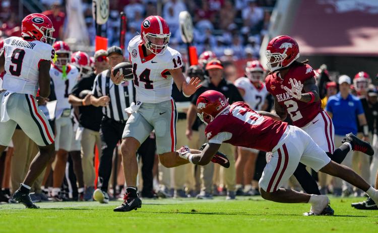 Tony Walsh/UGAAA. Former Rabun County and current Georgia quarterback Gunner Stockton (center) fights off Arkansas defenders during Georgia’s 45-17 win over Arkansas on Sept. 19. Stockton threw for 147 yards and a touchdown, and ran for 97 yards in the win.
