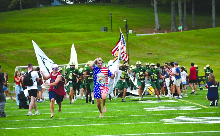 Enoch Autry/The Clayton Tribune. With junior tight end Cash Washburn carrying the American flag, Rabun Gap runs onto the field on a night the 9/11 attack was remembered.