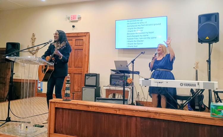 Megan Horn/The Clayton Tribune. Debbie Peack-Catrina, left playing the guitar, and Angel McCuen praise Jesus and lead worship music in the sanctuary at the 10-year celebration of Freedom Ministries Lighthouse on Saturday, Sept. 12.