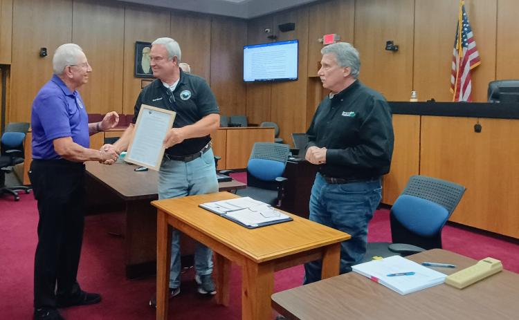 Megan Horn/The Clayton Tribune. Vietnam Veteran Bruce Gant, left, is presented with the framed proclamation from Commissioner Kent Woerner designating Rabun County as a “Purple Heart County.” Gant is a two-time Purple Heart Recipient and was honored at the meeting along with Purple Heart recipient Roy DeFoor. Commission Chairman Greg James called the men heroes.