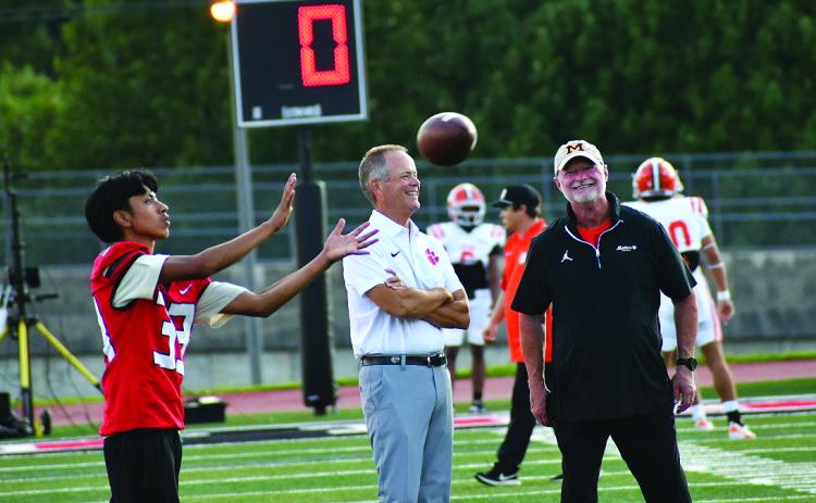Enoch Autry/The Clayton Tribune. With Wildcat Yiar Avila catching a football in front of them, Rabun County head coach Rance Gillespie (left) talks with former RCHS head coach and current Metter head coach Lee Shaw prior to the Aug. 28 matchup between the two teams in Tiger. RCHS won the back-and-forth contest 27-23 to begin 1-0.