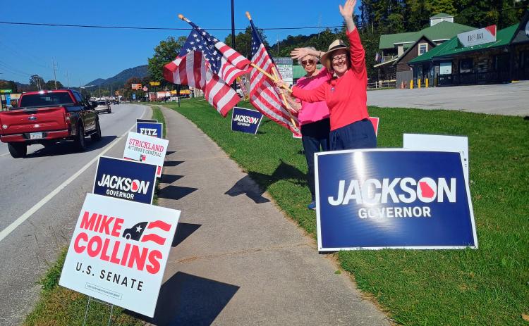 Megan Horn/The Clayton Tribune. Rabun County Republican Party Chair Benita Cotton-Orr and Treasurer Linda Burns encourage citizens to vote during a flag waving event held outside The Rusty Bike Cafe on the first day of early voting, Oct. 13.