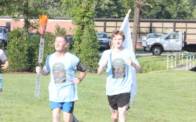 Anthony Lampros, left, and Guy Gober near the finish line at Rabun County’s new pavilion during the Bicentennial Torch and Flag Run in Clayton on Saturday morning. (Glendon Poe/The Clayton Tribune)