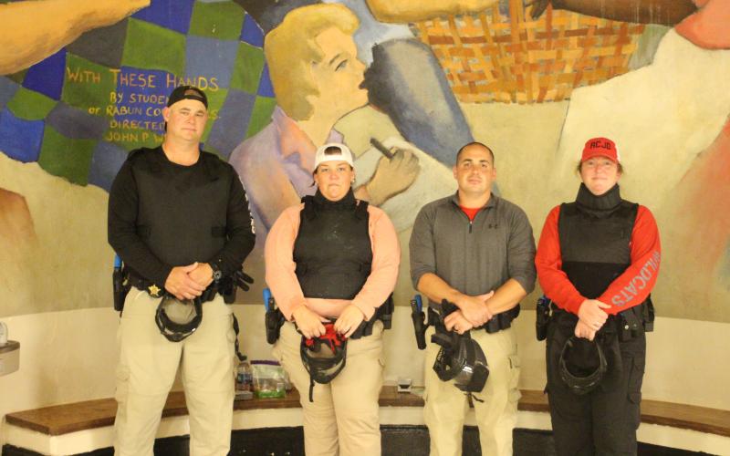 Megan Broome/The Clayton Tribune. Rabun County School Resource Officers (SROs) Sgt. Tim Brown, Deputy Beth Darnell, Deputy Chris Bartolomey and Deputy Lisa Thompson don their protective gear to train in the Heightened Emergency Response Officer (HERO) program at Rabun County Middle School on July 31 in preparation for the new school year. Lt. Mark Gerrells from the Rabun County Sheriff’s Office trains the SROs on this program.