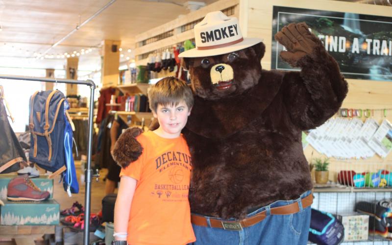 Megan Broome/The Clayton Tribune. Wiley Perreault, 10, poses with Smokey Bear at Wander North Georgia on Monday. Representatives of the Georgia Forestry Commission walked around downtown Clayton to educate the community on fire risk during a drought and how to prevent wildfires.