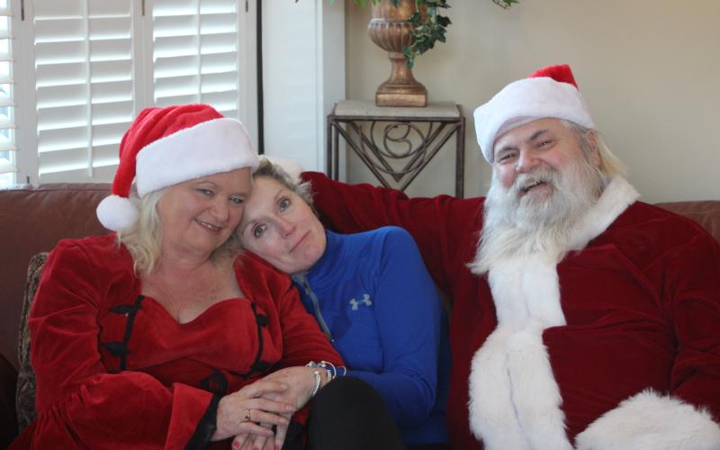 Megan Broome/The Clayton Tribune. Wanda Findley, middle, poses for a picture with her friends and neighbors MaryJane Phillips and Thomas Phillips, who travel around Georgia every year to portray Santa and Mrs. Claus. They give out presents to special needs and terminally ill children.