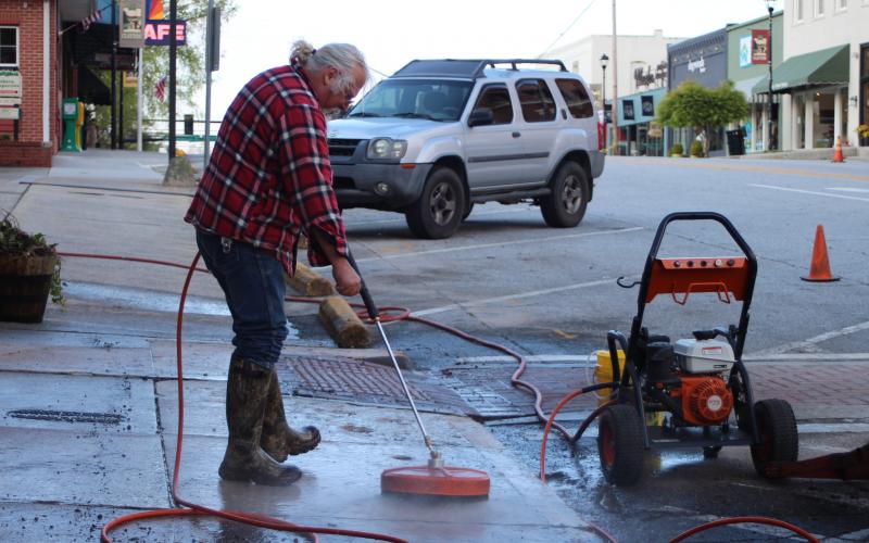 Megan Broome/The Clayton Tribune. Rob Hawsey with the streets department pressure washes the sidewalk on Main Street Tuesday. 