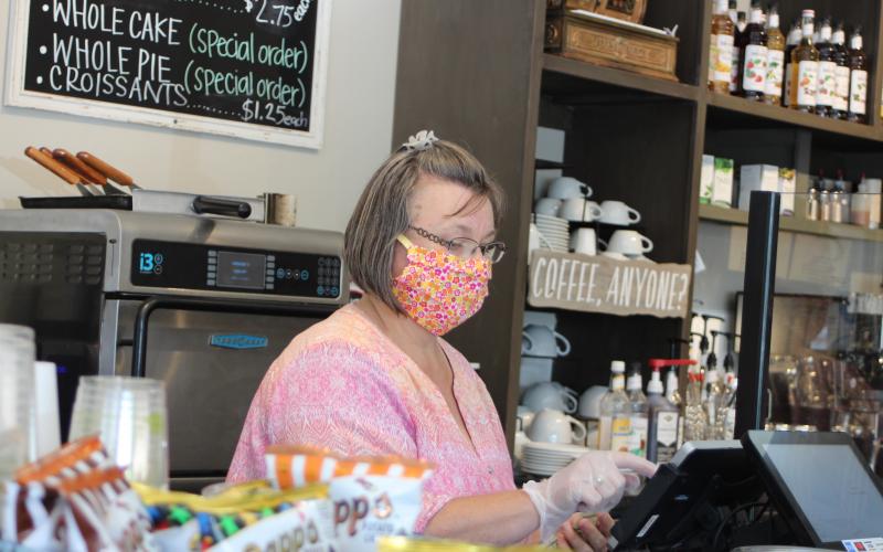 Megan Broome/The Clayton Tribune. Teka Earnhardt, manager of The Market on Main Street in Clayton, wears a mask and gloves to take a customer’s order. She said that employees are being extra cautious when it comes to safety and wash their hands often amidst the COVID-19 pandemic. 