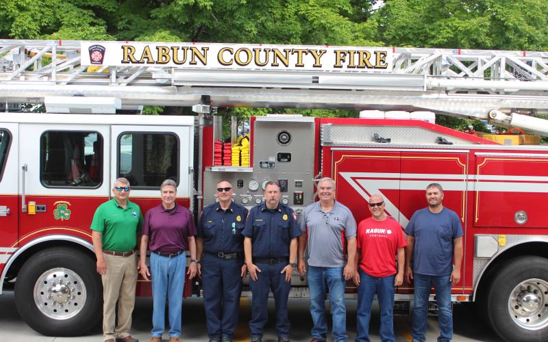 Megan Broome/The Clayton Tribune. Rabun County Fire Services put the county’s first ladder truck into service recently. It responds to fire and rescue calls across the county. Pictured from left are Darrin Giles, county administrator, Greg James, commissioner chairman, James Reed, fire chief, Justin Upchurch, assistant fire chief, and Commissioners Kent Woerner, Scott Crane and Will Nichols.