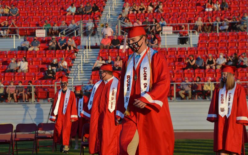 Wayne Knuckles/The Clayton Tribune. Under fair skies and a nearly-full moon, the Rabun County High School Class of 2020 received diplomas Saturday at Frank Snyder Memorial Stadium. Pictured: Andrew O'Brien, left, Cole Littrell and Will Hightower take their places. 