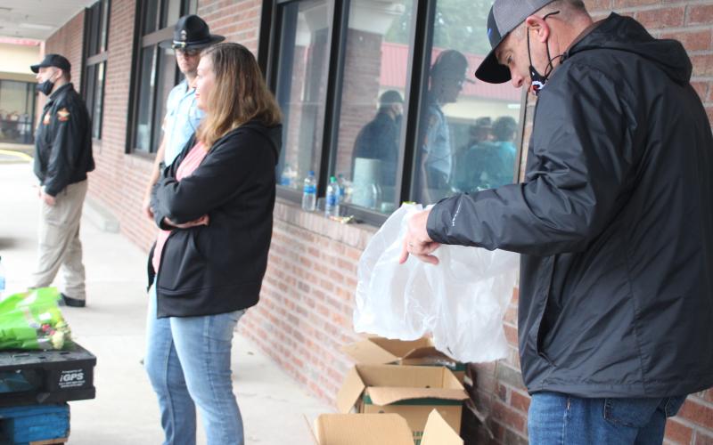 Megan Broome/The Clayton Tribune. Sgt. Casey Coffee of Georgia State Patrol, left, Investigator Channon Pritchard of the Rabun County Sheriff’s Office and Sheriff Chad Nichols distribute food to families last Saturday. 