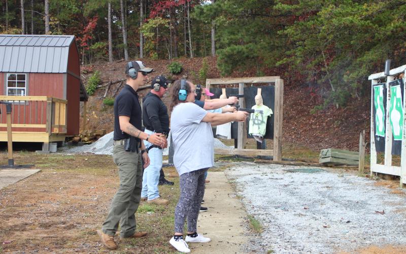 Megan Broome/The Clayton Tribune. Deputy Ryan Brown helps Jonnie Brown with her technique for shooting at moving targets last Saturday. 