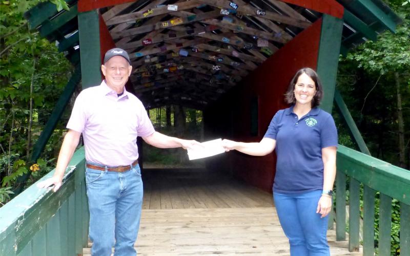 Submitted photo. Lake Burton Civic Association President Mike Hammer, left, presents a check to Jeanie Cook Camp Evergreen.