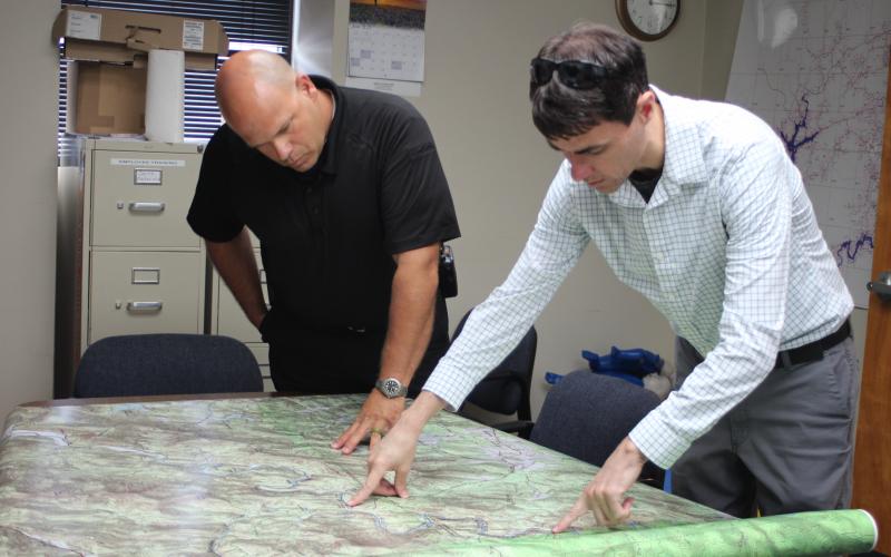 Megan Broome/The Clayton Tribune. Brian Panell, new EMA director, left, and Troy Keenan, head of the Rabun County mapping department, look over a map of an area of Rabun County and brainstorm ideas of how to improve radio communication in the area.