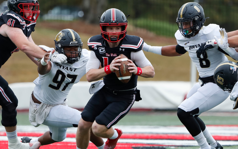 Courtesy of Gardner-Webb Athletics. Gardner-Webb redshirt senior Bailey Fisher evades two tackles in a game against Bryant on Oct. 29. Fisher, a former Rabun County Wildcat, threw for five touchdowns that day in the middle of his campaign to win Big South “Offensive Player of the Year.” 