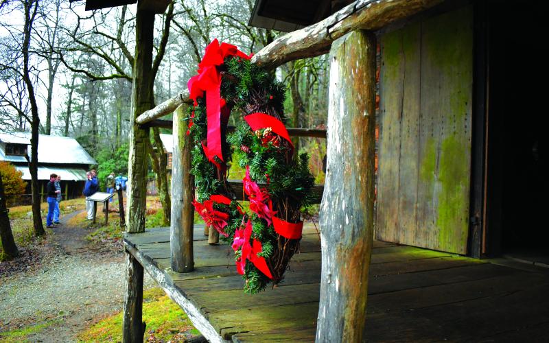 Enoch Autry/The Clayton Tribune. A wreath is on display near the Grist Mill as visitors enjoy the property.