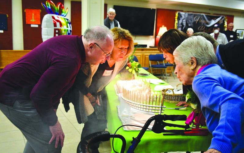 Megan Broome/The Clayton Tribune. Allie Moseley, right, blows out 100 candles on her birthday cake with help from friends and family members Bo Cribbs, Debby Moseley, and Cindy Wallis. Friends and family members gathered for Moseley’s centennial birthday party on Dec. 5. 