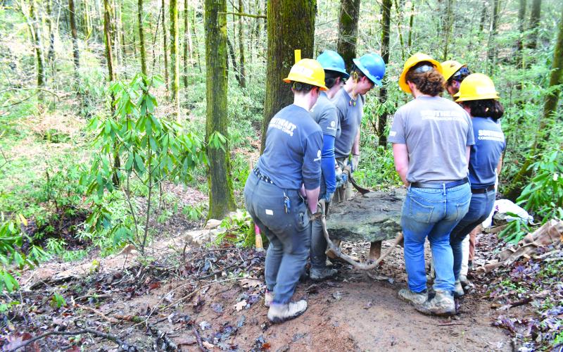 Megan Broome/The Clayton Tribune. Crew members with the Southeast Conservation Corps work together to carry large and heavy stones to a portion of the Bartram Trail at Warwoman Dell in order to build a set of stone stairs on the popular and highly-used trail. 