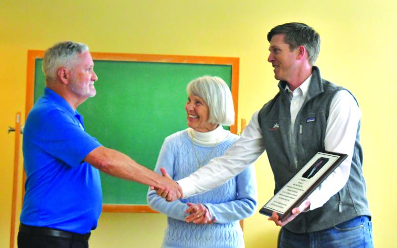 Megan Broome/The Clayton Tribune. Rotarian Tim Ranney, chair of Clayton Rotary Foundation, Inc., (left) presents a memorial plaque for Robert “Bob” Noble Fink and shakes hands with Fink’s wife Gwen Fink and grandson Robert Fink III during a dedication.