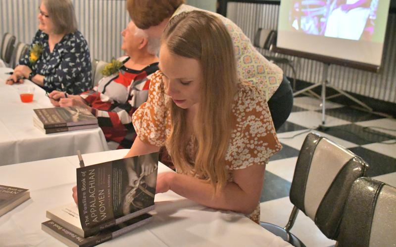 Megan Broome/The Clayton Tribune. Kami Ahrens, curator and director of education for Foxfire, signs a book she wrote and edited titled “The Foxfire Book of Appalachian Women: Stories of Landscape and Community in the Mountain South” during a book launch event held at the Rabun County Civic Center Diner Saturday, March 11. 