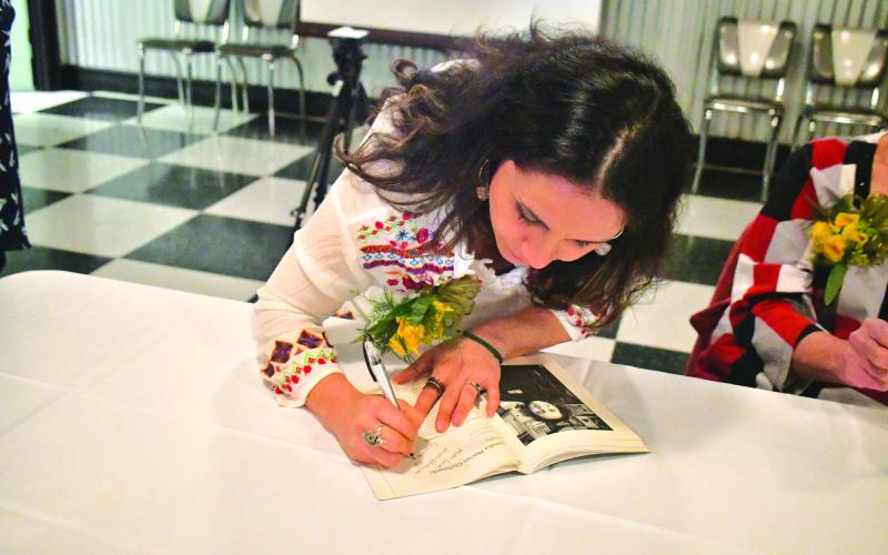Megan Broome/The Clayton Tribune. Sandra Macias Glichowski, one of the women featured in the book signs the publication at the launch on March 11.  