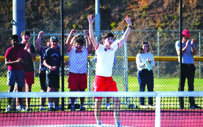 Luke Morey/The Clayton Tribune. With his teammates and classmates cheering in the background, RCHS freshman singles tennis player Brady Darnell raises his arms in victory for his three-set Tuesday win that propelled the Wildcats into the Sweet Sixteen.