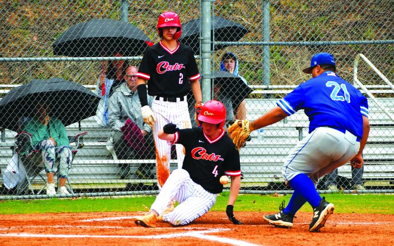 Luke Morey/The Clayton Tribune. With freshman Ty Truelove looking on, Rabun County senior Nathan Thompson slides into home plate on Thursday, April 13 against Barrow Arts and Sciences Academy.  