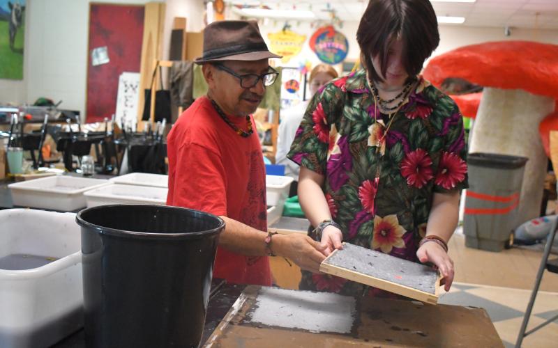 Megan Broome/The Clayton Tribune. Artist Javier Silverio, director of Taller Leñateros in Chiapas, Mexico, works with student  Audrey Schomburg while making paper in the Rabun County High School art room April 21.