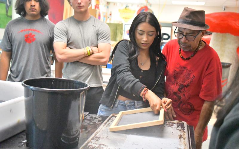 Megan Broome/The Clayton Tribune. Student Giselle Canales is shown how to make paper using natural materials and dye by artist Javier Silverio, director of Taller Leñateros in Chiapas, Mexico in the art room at Rabun County High School April 21.