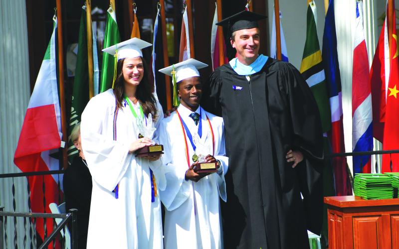 Luke Morey/The Clayton Tribune. During graduation on Sunday, May 21, Rabun Gap Head of School Jeff Miles awards Crystal Eagles to two seniors who exemplify the most school spirit. The award winners were Cheney Moriarty (left) and Benit Jabo. 