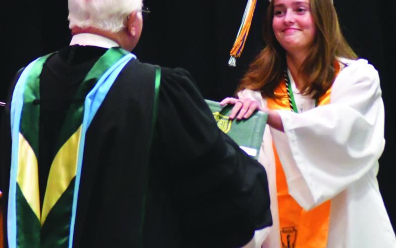 Enoch Autry/The Clayton Tribune. National Honor Society member TFS senior Ellesen Eubank receives her diploma from Dr. Larry A. Peevy.