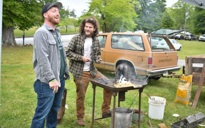 Megan Broome/The Clayton Tribune. Clayton resident Conner Horn enjoys conversation with blacksmith Eli Bundrick as he completes a demonstration of his craft at Dinglerfest in Dillard Saturday, May 6. 