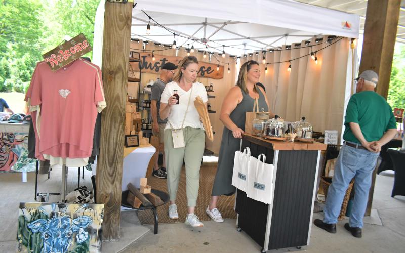 Megan Broome/The Clayton Tribune. Ara Joyce with Just Cause happily converses with community members at the Of These Mountains Spring MarketPlace held in downtown Clayton Clayton Saturday, May 13.