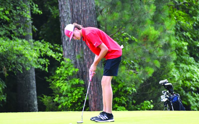 Luke Morey/The Clayton Tribune. RCHS’s Owen Thompson putts his ball into the hole at state Tuesday.