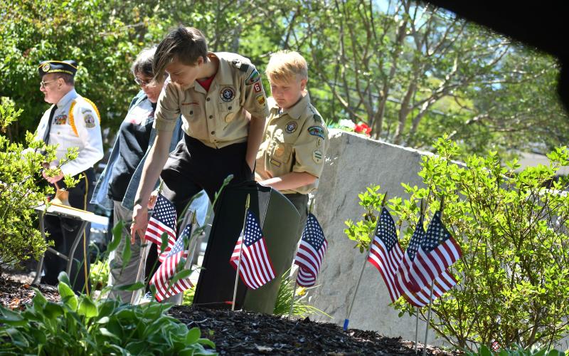 Megan Broome/The Clayton Tribune. Boy Scouts place flags as the names of the veterans who died since last Memorial Day were read aloud.