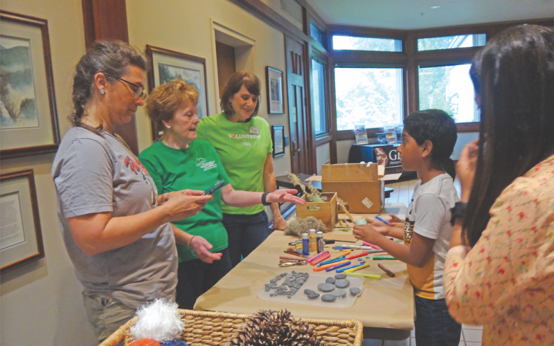 Submitted photo. Rabun High School art teacher Amy Jarrard (from left) and Friends of TGSP volunteers Pat Coleman and Shirley Atkinson help children with arts and crafts at the art station at the 30th anniversary event.