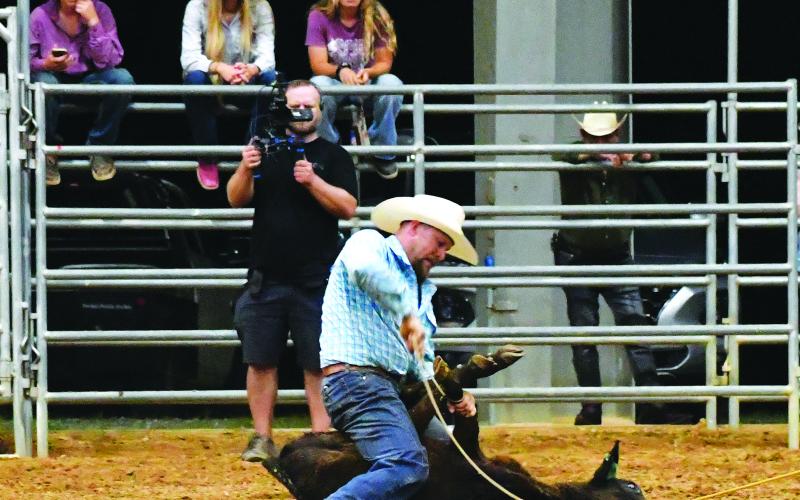Luke Morey/The Clayton Tribune. Clint Thomas wrestles down a calf during the calf roping segment of the rodeo on Friday, June 30. While Thomas didn’t place in the first night, Thomas took first place on Saturday, July 1.