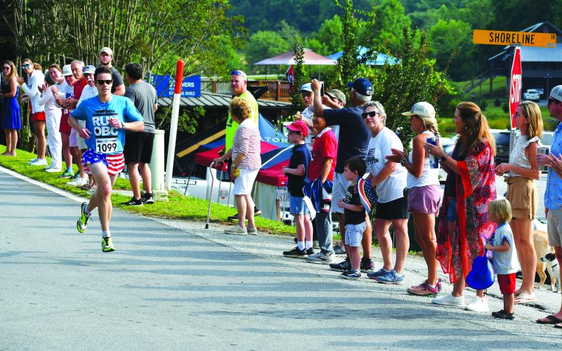 Luke Morey/The Clayton Tribune. With the onlookers cheering him on, Noah Schaich of Fort Collins, Col. crosses the finish line as the first runner to complete the 39th annual Lake Burton Fun Run.