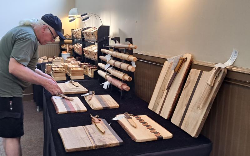 Megan Broome/The Clayton Tribune. Frank Marino looks at custom cutting boards and other wooden creations by Jerry and Nancy Williamson of J.W. Wood Boxes & Gifts during the Painted Fern Art Festival at the Rabun County Civic Center July 8.