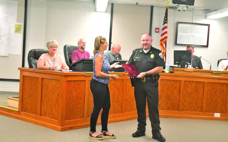Megan Broome/The Clayton Tribune. Clayton City Manager Trudy Crunkleton presents Clayton Police Department Chief Andy Strait with a plaque recognizing him for 25 years of service to the community during Tuesday’s Clayton City Council meeting.