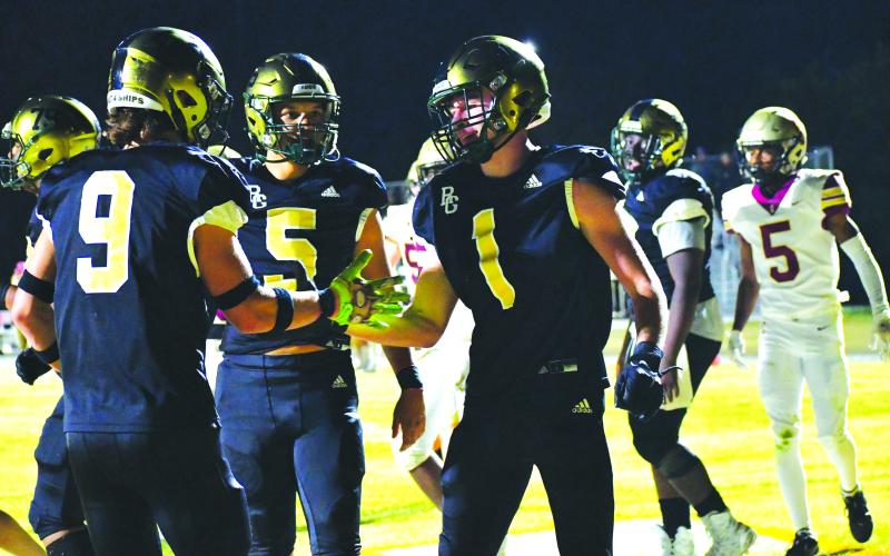 Luke Morey/The Clayton Tribune. Junior Trey Horne (1) celebrates with teammates Marshall Pritchett (9) and Gavin Owens after Horne’s fourth touchdown of the night in the playoffs in November 2022.