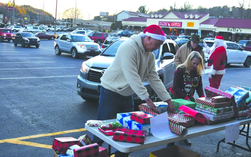 Enoch Autry/The Clayton Tribune.  Food Bank of Northeast Georgia Branch Manager James Brim and Victoria Anderson help with the presents that are given out to the children at the outdoor event in the Covered Bridge Shopping Center. 