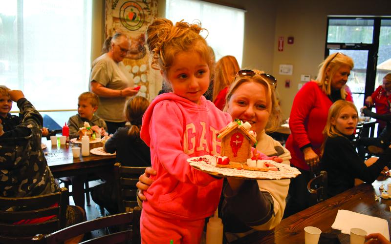 Megan Horn/The Clayton Tribune.  Lyndi Cox, 4, with Courtney Cox is excited about her gingerbread house that features a cross on the front door.  
