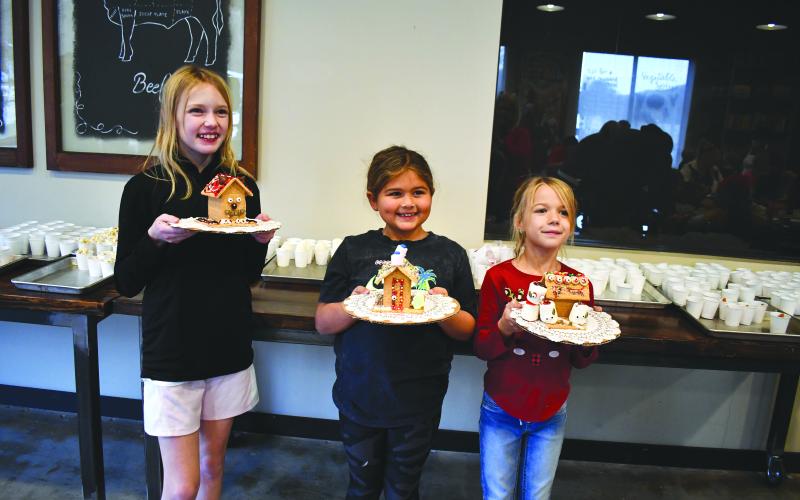 Megan Horn/The Clayton Tribune. Aubree Phillips, 10; Blake Ruiz, 7, and Lila Phillips, 7, are excited after decorating their gingerbread houses.