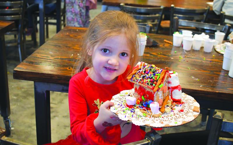 Megan Horn/The Clayton Tribune. Addison Parker, 6, went all out decorating her gingerbread house at the Teaching Kitchen Dec. 13.  