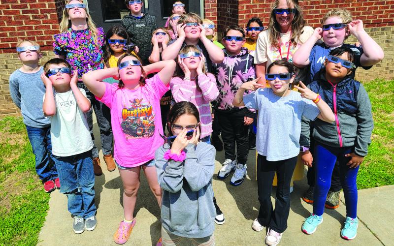 Enoch Autry/The Clayton Tribune. Students from the classes of Kelsey Alexander and Michelle Faircloth look at the eclipse. Left: Hudson Hamby sees the Eclipse in the sky Monday.