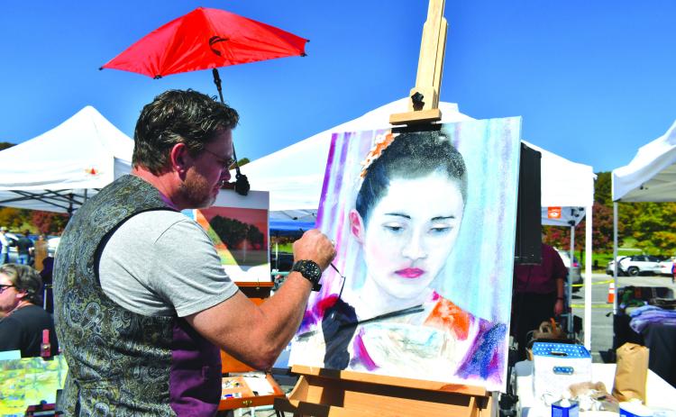 Megan Broome/The Clayton Tribune. Megan Broome/The Clayton Tribune. Alan Corbett showcases his talent and paints a portrait while visitors check out the various crafts and artwork set up during the Sky Valley Fall Fest last weekend. 