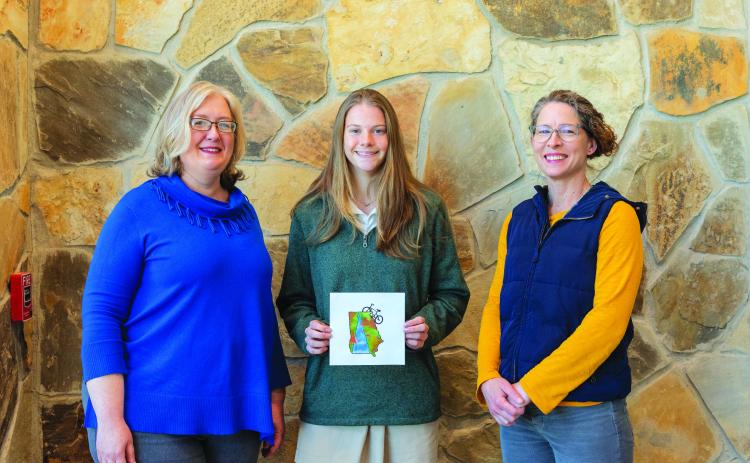 E. Lane Gresham/Tallulah Falls Schools. Tallulah Falls School senior Kaylin Neal of Flowery Branch produced the winning artwork in a student art contest for the 2022 Twin Rivers Challenge T-shirt. Shown, from left are Smith, Neal and art teacher Stephanie Stuefer. 