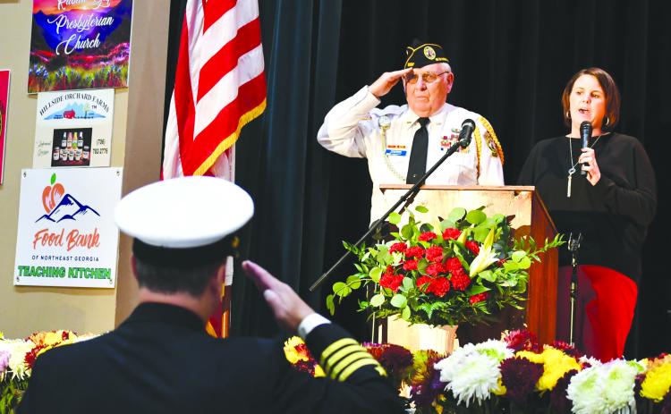 Megan Broome/The Clayton Tribune. Veteran Doug Wayne and fellow soldiers salute the American Flag as Lora Burrell sings The Star-Spangled Banner at the opening of the Veterans Appreciation Dinner held at the Rabun County Civic Center. 