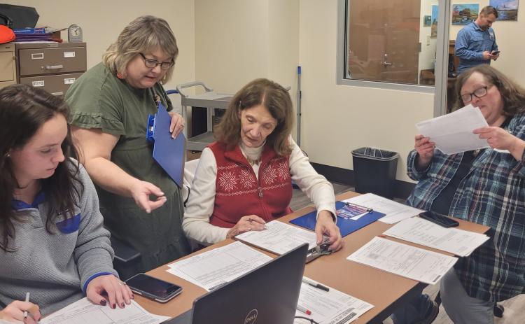 Megan Broome/The Clayton Tribune. Shay Harbin, office assistant; and poll workers Lynne Ramey; Kathy Allen, and Amanda Burrell work at the Rabun County Board of Elections Office after polls closed for the Dec. 6 U.S. Senate runoff, which saw over 50 percent of voters in Rabun County cast their ballots. Shown in the background is Zarek Echols, technician. 